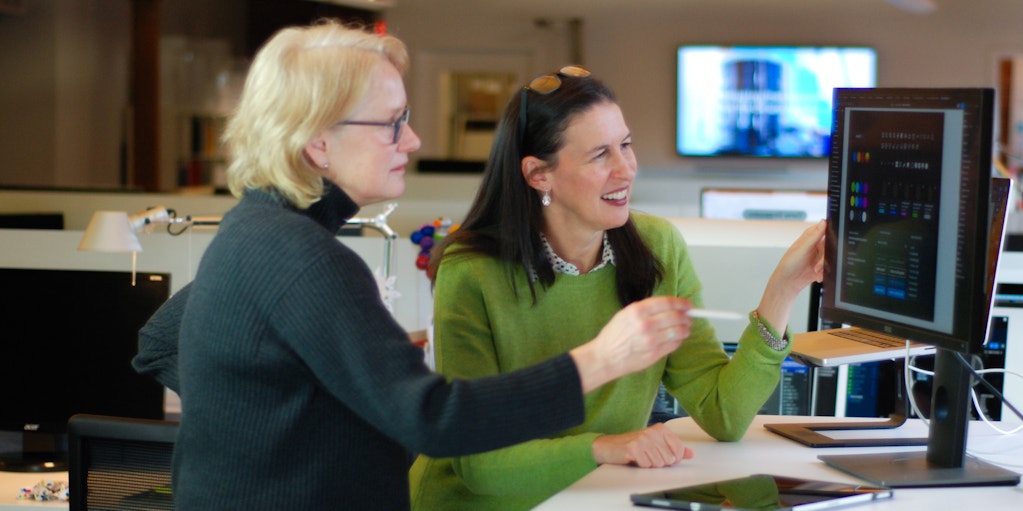 Melanie and a designer reviewing a design on a computer screen