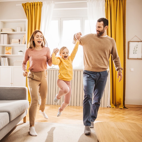 Parents picking up child in sunny room