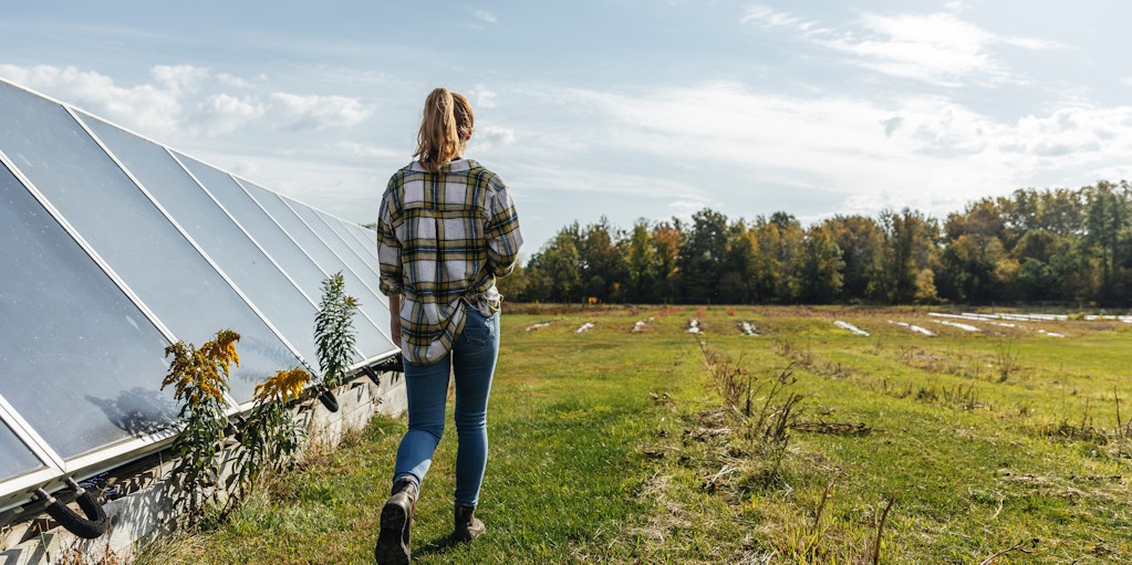 Farmer walking past greenhouse towards field