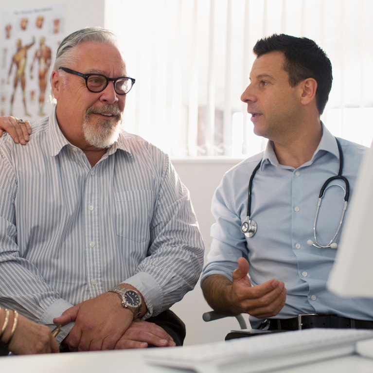 Doctor meeting with senior couple at computer in doctors office