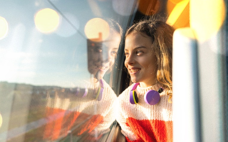 Girl wearing headphones looking out the window on train