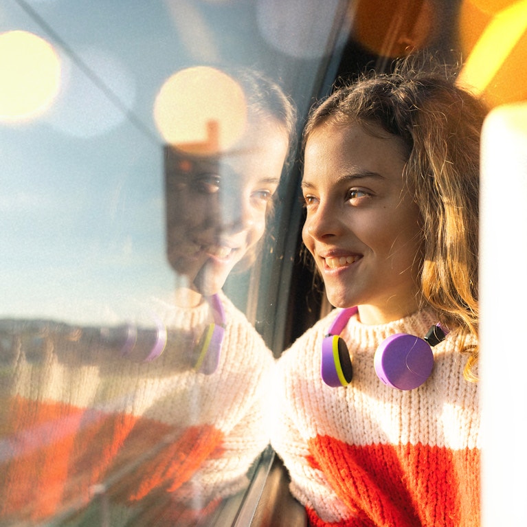 Girl wearing headphones looking out the window on train
