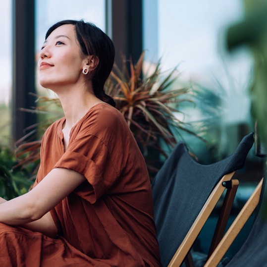 A woman inside an indoor garden sitting down