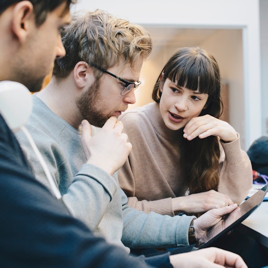 Male and female computer programmers discussing over digital tablet at desk in office