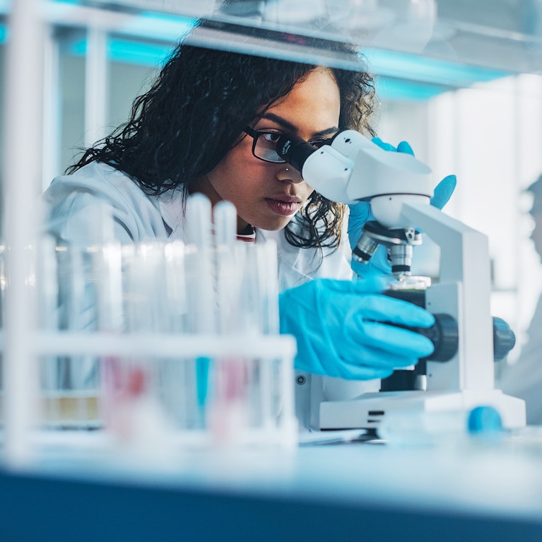 Life sciences researcher looking through microscope