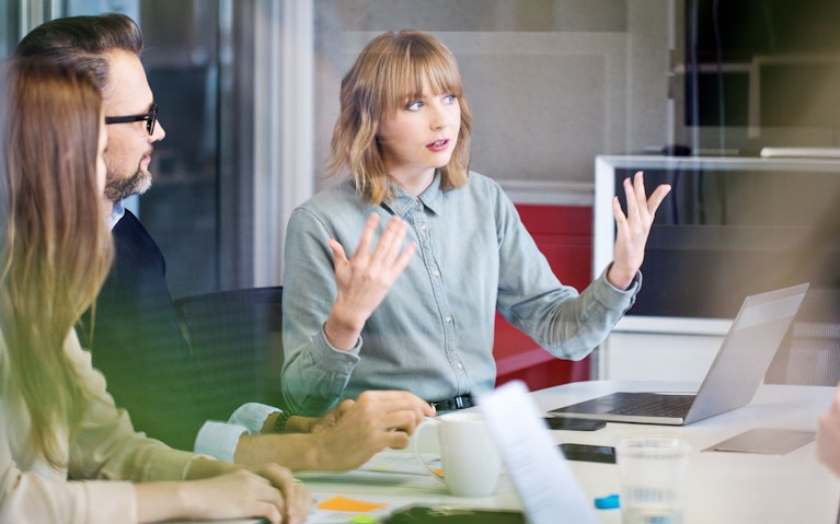 Person speaking to others in an office meeting room