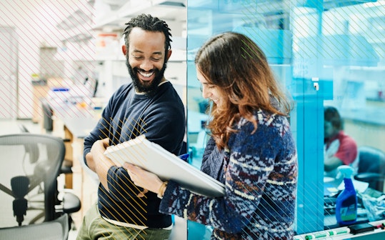 Two people in an office smiling and talking to each other