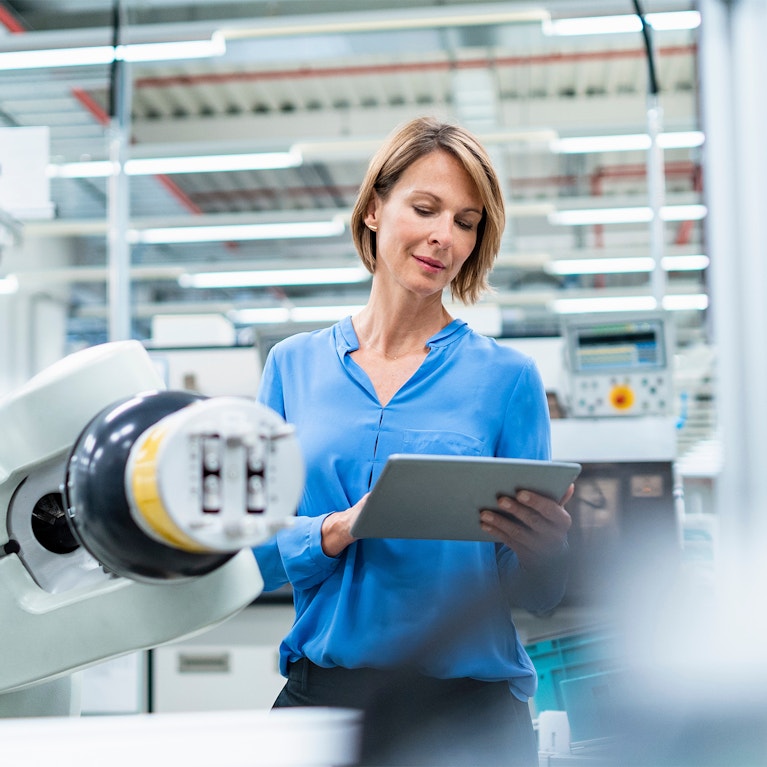Businesswoman with tablet at assembly robot in a factory