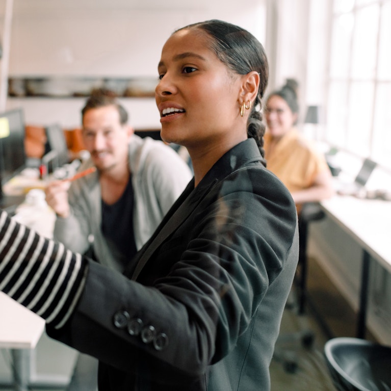 Young businesswoman addressing colleagues at office meeting