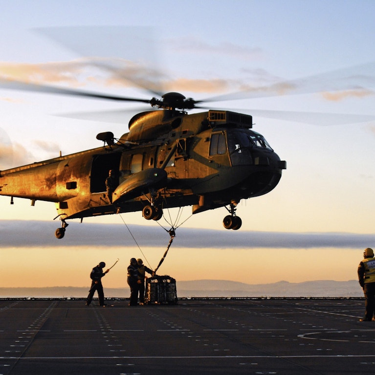Military helicopter against sunset background.