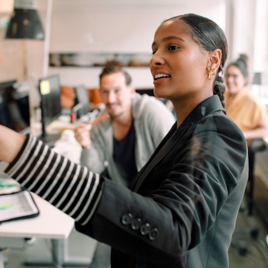 Young businesswoman addressing colleagues at office meeting