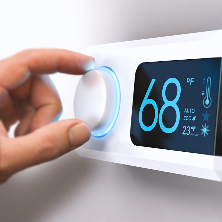 Electric thermostat set to 68°F with hand on the dial