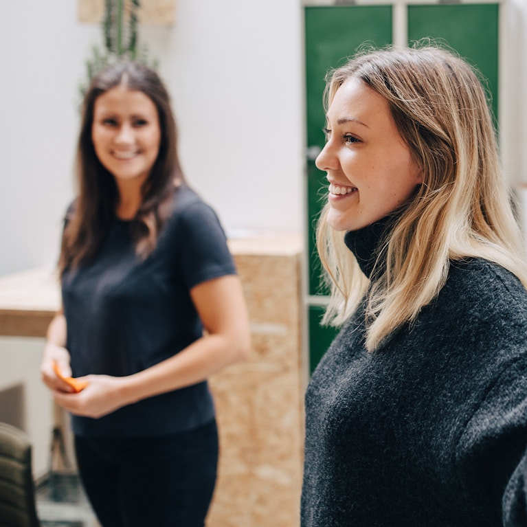 Side view of smiling businesswoman explaining adhesive notes stuck on glass wall in meeting.