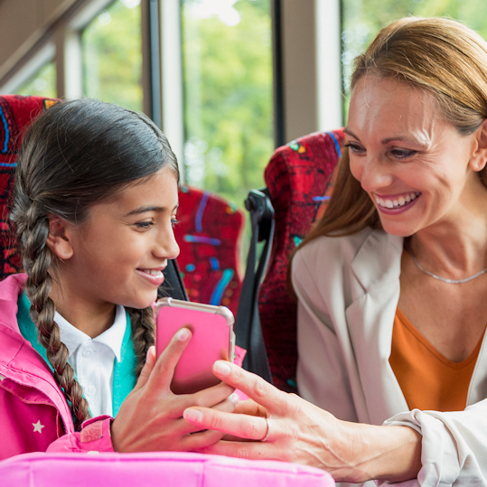 Parent and child on public transport looking at phone