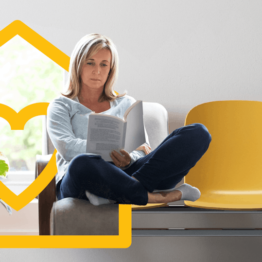 Woman seated on row of chairs reading document