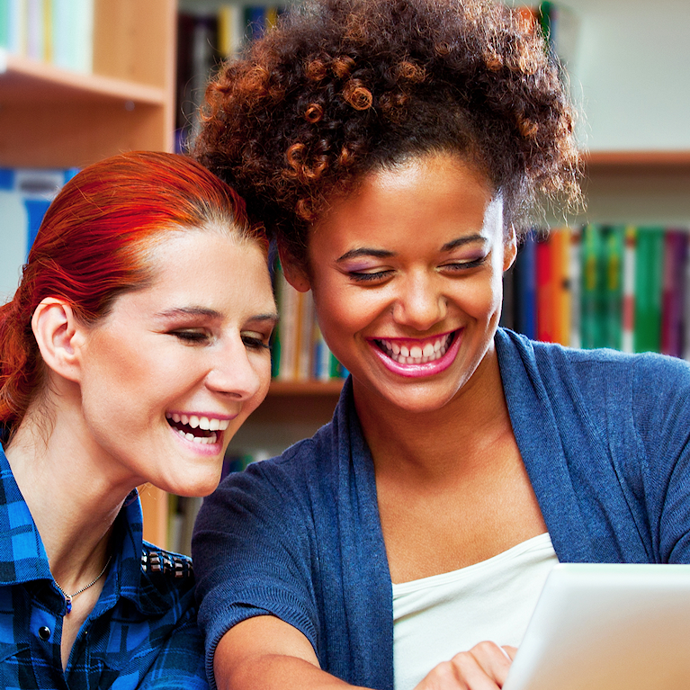 Two people smiling together whilst looking at soemthing