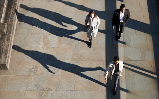 Aerial view of three people dressed in business attire walking down a city street