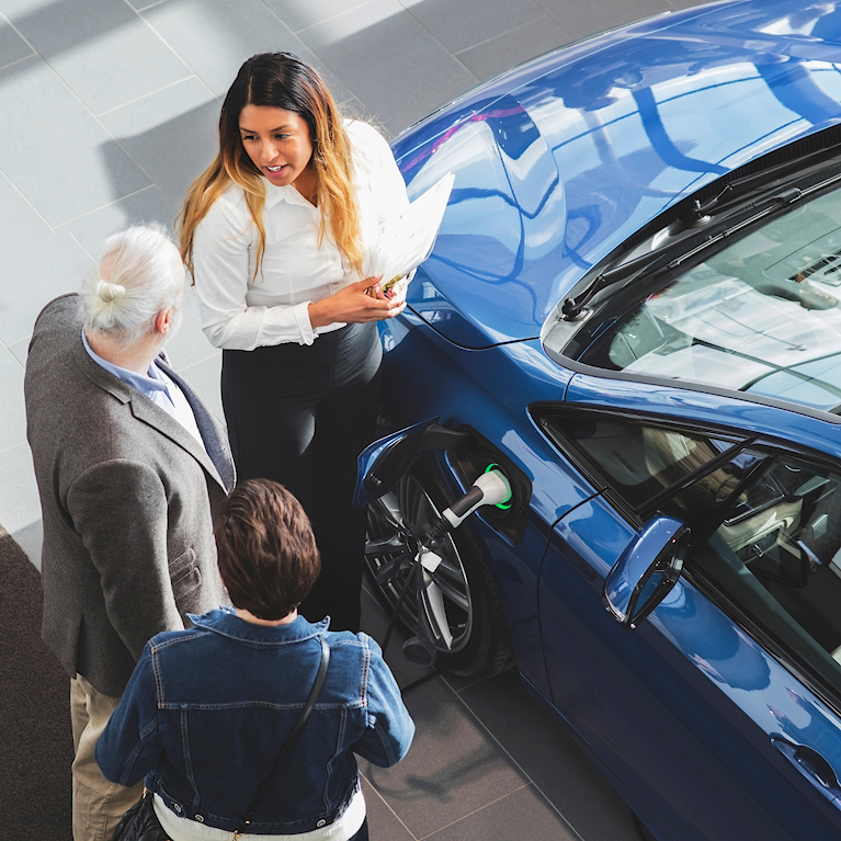 three people standing next to car
