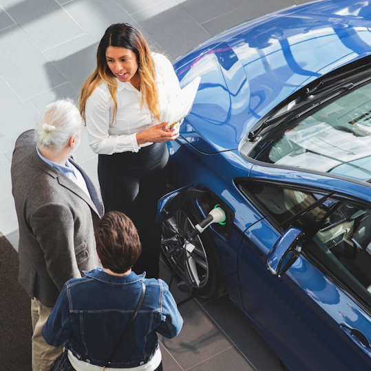 three people standing next to car